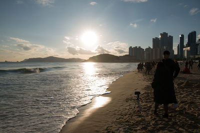 Rear view of silhouette man on beach against sky during sunset