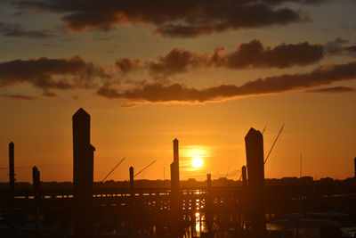 Silhouette factory against sky during sunset