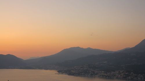 Silhouette mountain by sea against clear sky during sunset