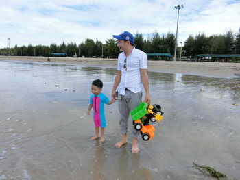Full length of father and son on shore at beach