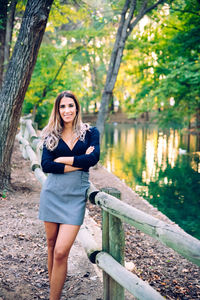 Portrait of young woman standing against trees