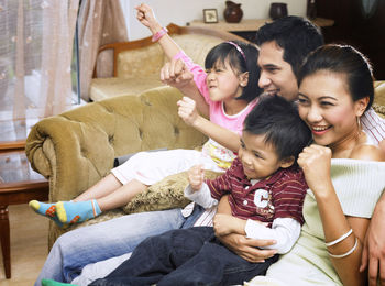 Cheerful family sitting on sofa at home