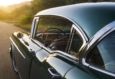 Photographs of a green cadillac standing in the middle of a lonely road at sunset