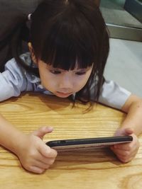 High angle view of girl using phone at table