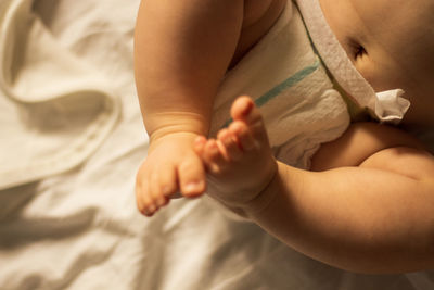 Low section of shirtless baby on bed