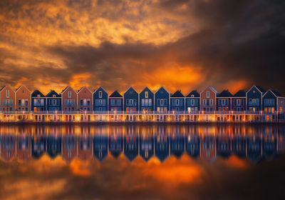 Buildings by sea against orange sky