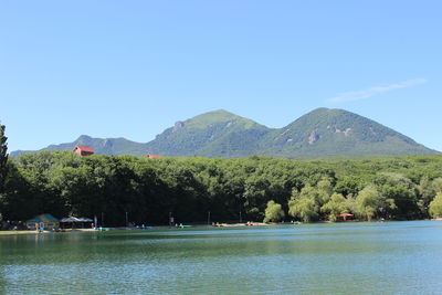 Scenic view of lake and mountains against clear blue sky