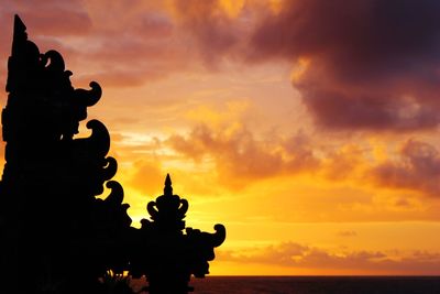 Close-up of silhouette statue against orange sky