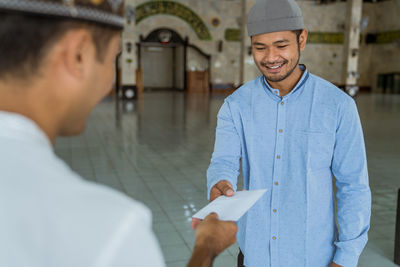 Smiling man receiving envelope in mosque