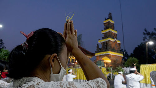 Rear view of woman holding umbrella against sky at dusk