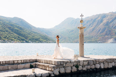 Woman standing on cross against mountains against sky