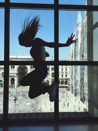 Low angle view of woman jumping behind window