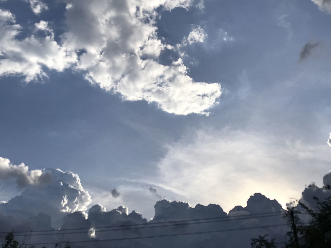 LOW ANGLE VIEW OF CLOUDS OVER SILHOUETTE MOUNTAINS AGAINST SKY