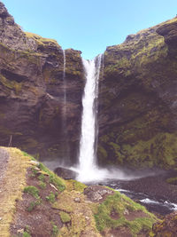 Scenic view of waterfall cliff mountains water sunny day holiday traveling wall nature lake sun 