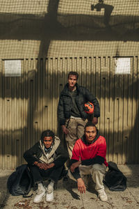 Portrait of multiracial young male friends posing against wall