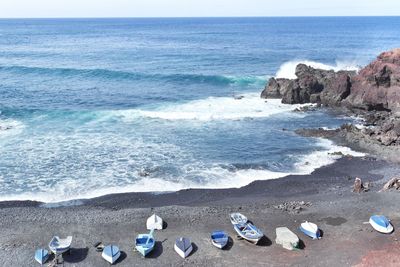 Boats moored on shore at beach by seascape