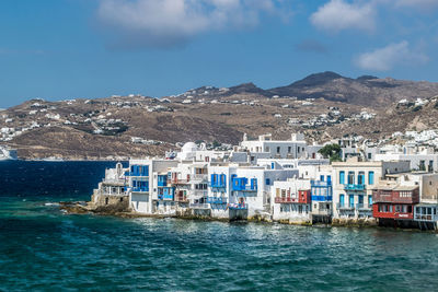 Buildings by sea against sky