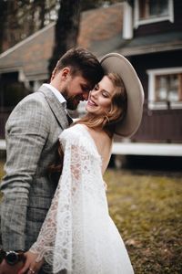 Couple embracing against house