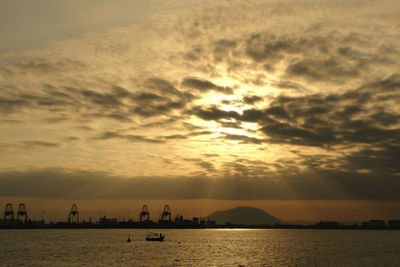 Scenic view of boat on sea against dramatic sky during sunset