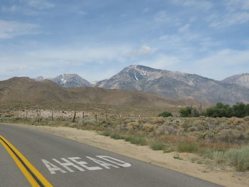 Road by mountains against sky