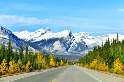 Road by snowcapped mountains against sky during winter