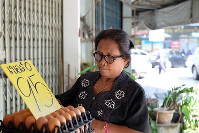 Woman looking at eggs in carton for sale at market