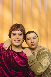 Happy non-binary couple standing together in front of yellow corrugated wall