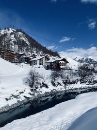 Scenic view of snow covered houses by mountain against sky