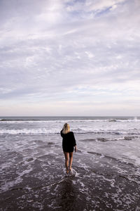 Rear view of young woman standing on beach