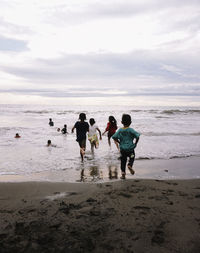 Children playing on beach against sky