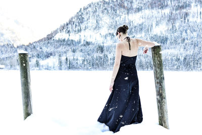 Woman standing on snow covered shore against sky