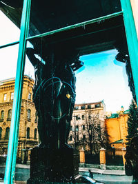 Low angle view of statue by city against sky