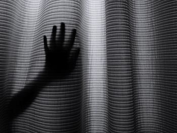 Silhouette hand touching curtain