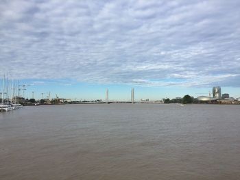 City at waterfront against cloudy sky