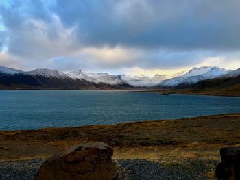 Scenic view of lake by mountains against sky