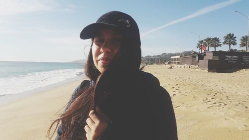 Portrait of woman standing at beach against sky