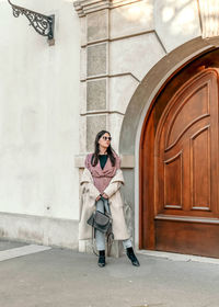 Young woman standing in front of old wooden door. fashion, lifestyle, posing.