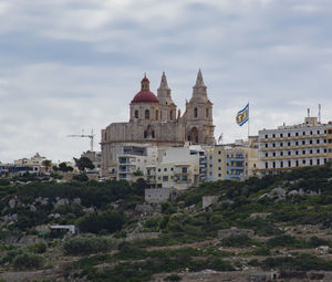 Buildings in city against cloudy sky