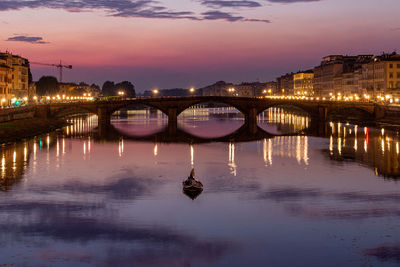 Illuminated bridge over river against sky at sunset