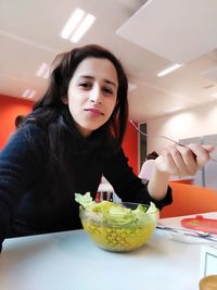 Portrait of young woman with ice cream on table