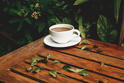 Coffee cup and leaves on table