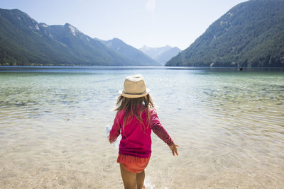 Rear view of toddler girl walking into chilliwack lake, b.c. canada.