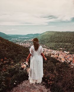 Rear view of woman standing on landscape against sky