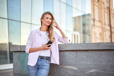 Beautiful young woman using mobile phone in city