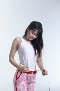 Woman measuring waist against white background