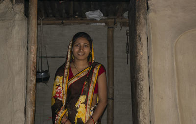 Portrait of smiling young woman standing at door