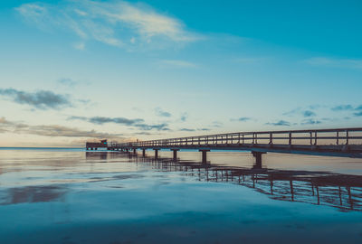 Bridge over sea against cloudy sky