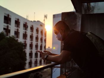 Side view of man photographing against sky during sunset