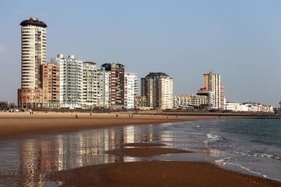 Sea by buildings against clear sky