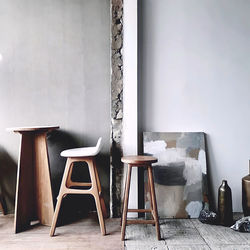 Empty chairs and table against wall at cafe